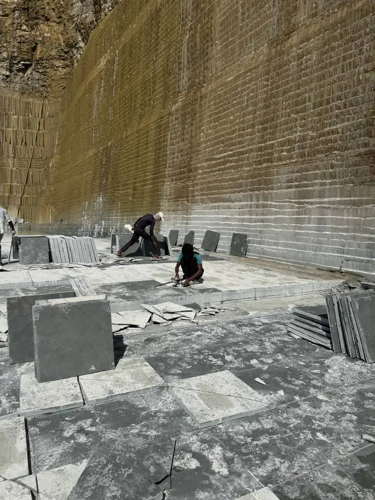 Kota stone slabs laid out below the saw-cut face of the quarry
