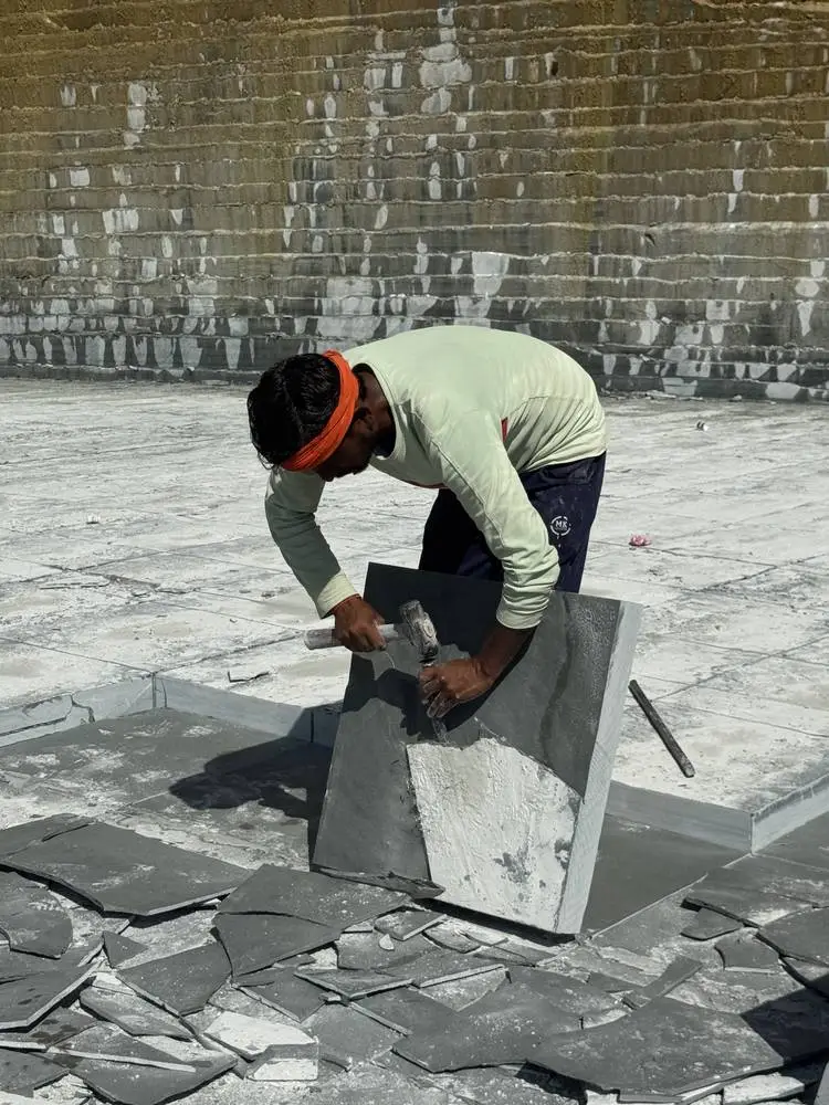 A worker squaring the edge of a Kota stone slab by hand