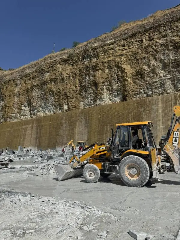 Excavator working at the base of the quarry wall
